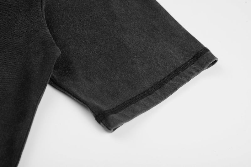 Close-up of a black vintage washed graphic tee sleeve with raw-edge hem and visible stitching on white background