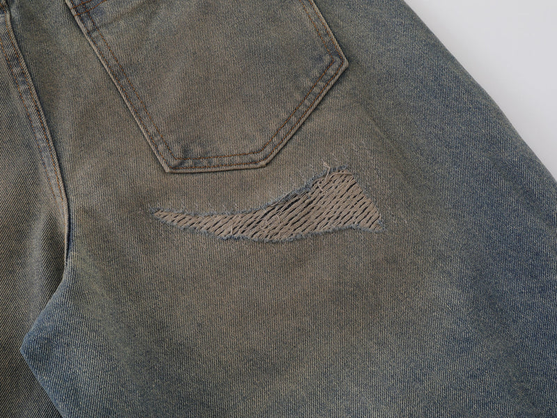 Close-up of distressed patch and curved seam on vintage wash denim