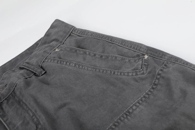 Close-up of gray shorts waistband and back pocket stitching on a textured cotton twill fabric