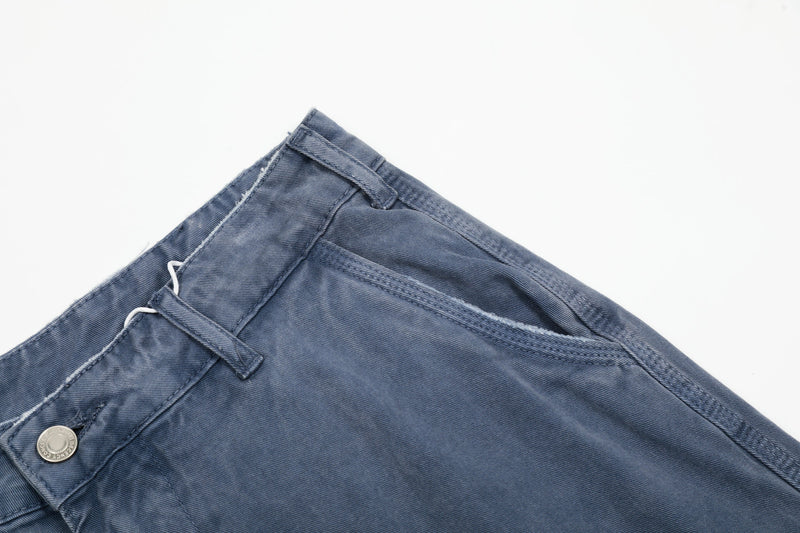 Close-up of washed blue pants waistband and front pocket area with button detail