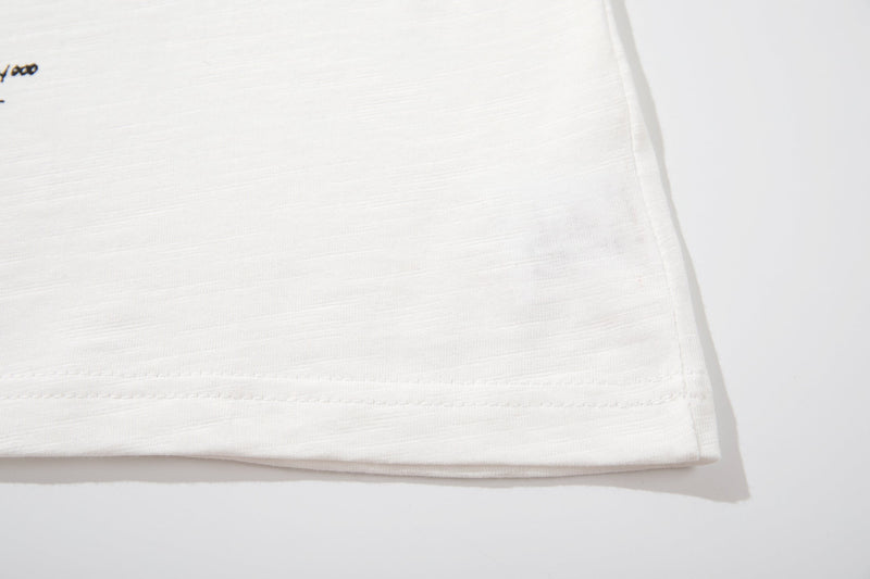 White graphic tee hem with subtle vintage print detail on a soft cotton band poster shirt
