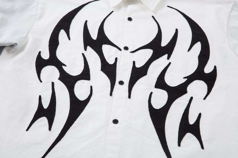 Front view close-up of black tribal flame print and button placket on white shirt