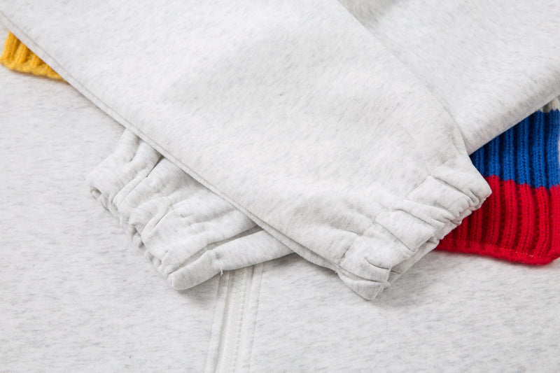 Close-up of the hooded sleeve cuffs and hem area on a light gray zip jacket