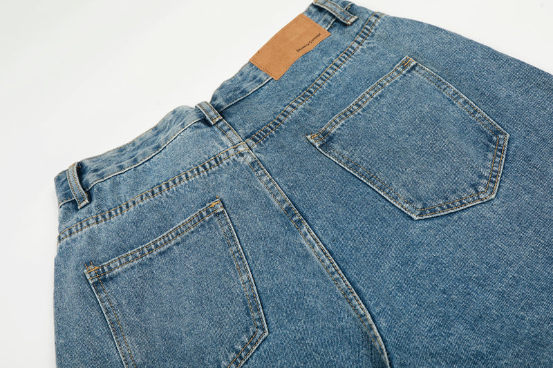 Back pocket close-up on blue wide-leg denim jeans with tan label above