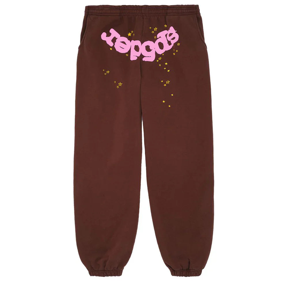 Sp5der Sweatpants: Unisex brown cotton joggers with playful pink front logo and scattered yellow star prints, offering standout streetwear style.