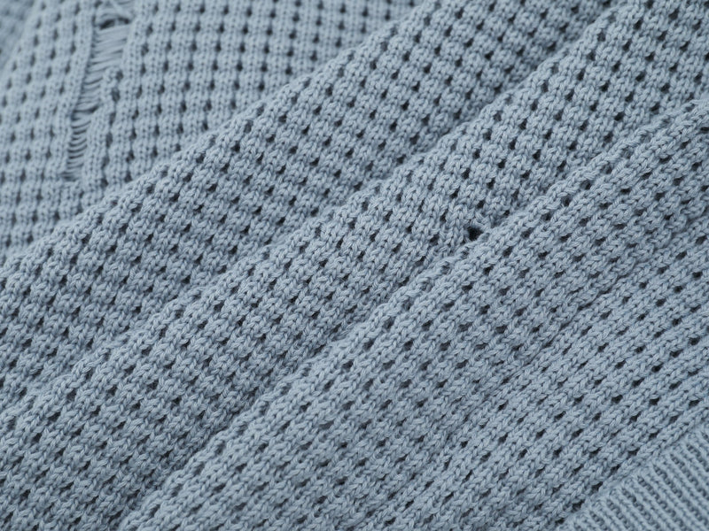 Close-up of light blue cardigan knit fabric with distressed vertical slit