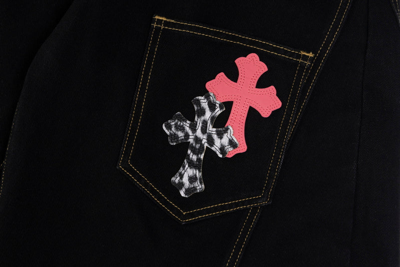 Single back pocket with one marbled black-and-white cross patch and a pink cross patch on black denim