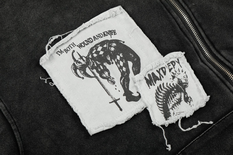 Close-up of two distressed graphic patches on black hoodie near the zipper