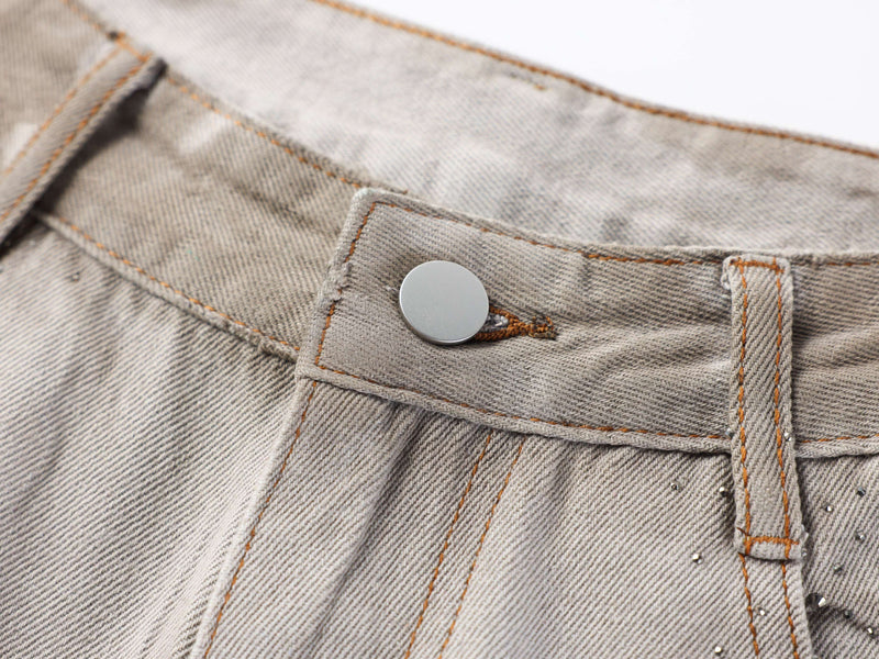 Close-up of the front waistband button and belt loop on washed denim pants