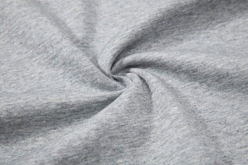 Close-up of light gray heathered knit fabric with soft folds and textured sweatshirt-like material