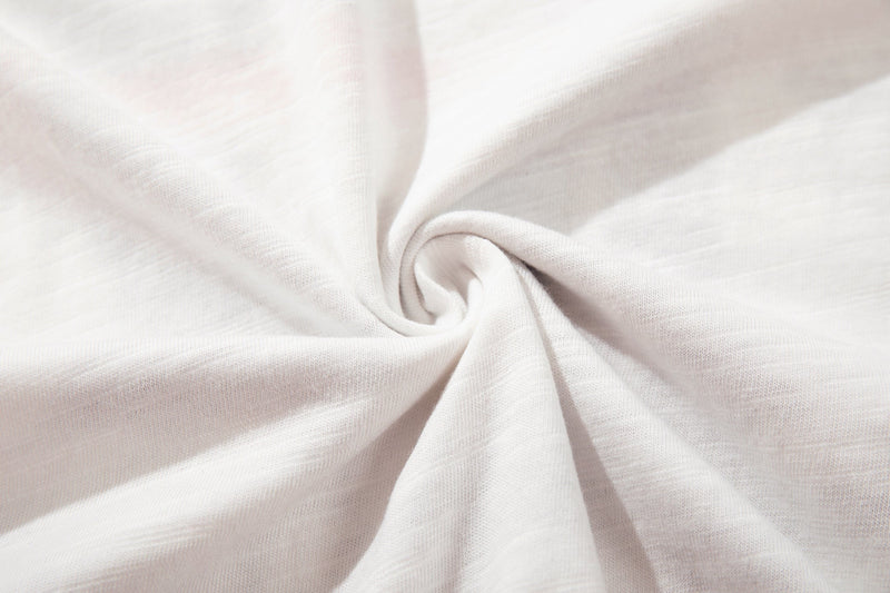 Close-up of white knit T-shirt fabric with a soft twisted center detail and subtle texture