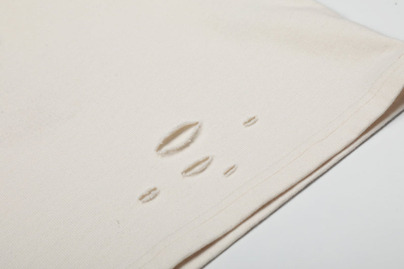 Cream vintage distressed band tee with small ripped holes and raw hem detail