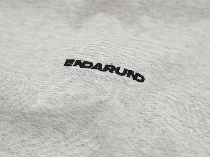 Close-up of embroidered black ENDARUND logo on heather gray fabric