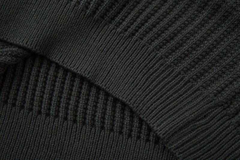 Close-up of dark ribbed knit sweater sleeve seam and ribbed cuff texture