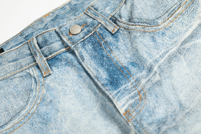 Close-up of jeans waistband with silver button, belt loops, and orange topstitching