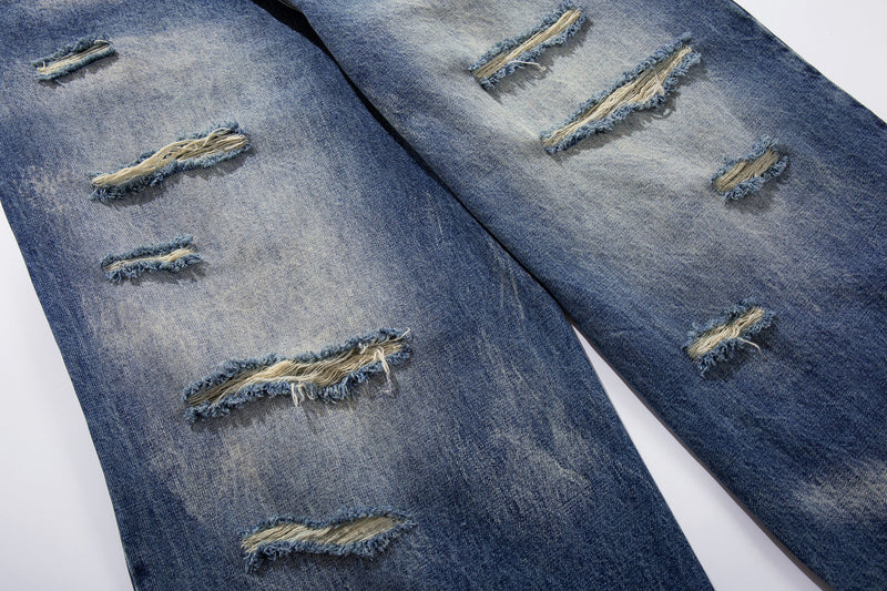 Distressed ripped sections on wide-leg blue jeans with frayed threads