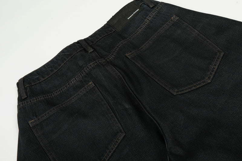 Close-up of black denim back waistband and patch pocket with brand label detail