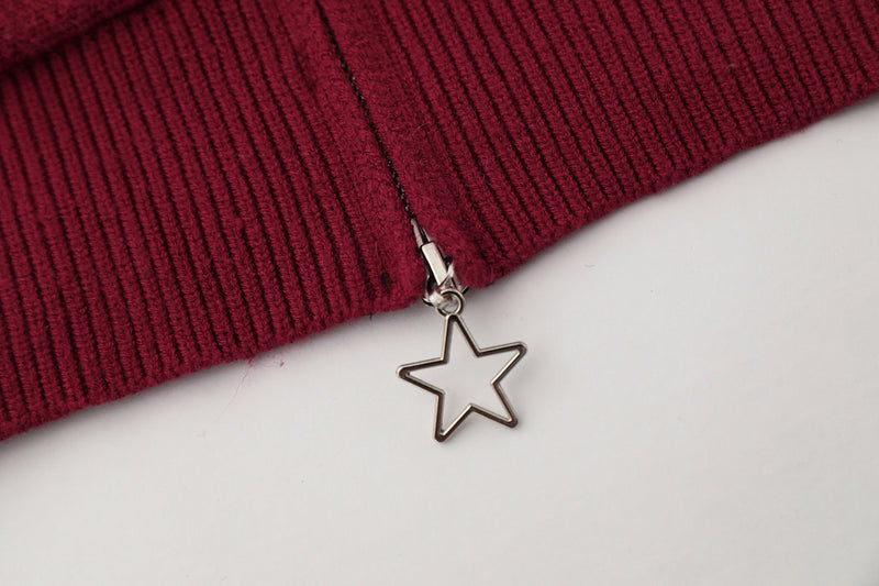 Close-up of burgundy hem zipper with dangling star charm and ribbed knit trim