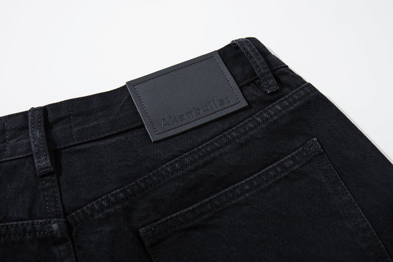 Close-up of the back waistband and leather brand patch on black denim jeans
