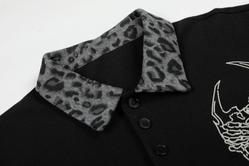 Black polo tee with gray leopard-print collar, button placket, and white graphic skull detail on the chest