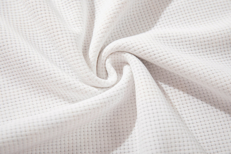 Close-up of soft white ribbed cotton fabric with a textured knit pattern and gentle folded drape