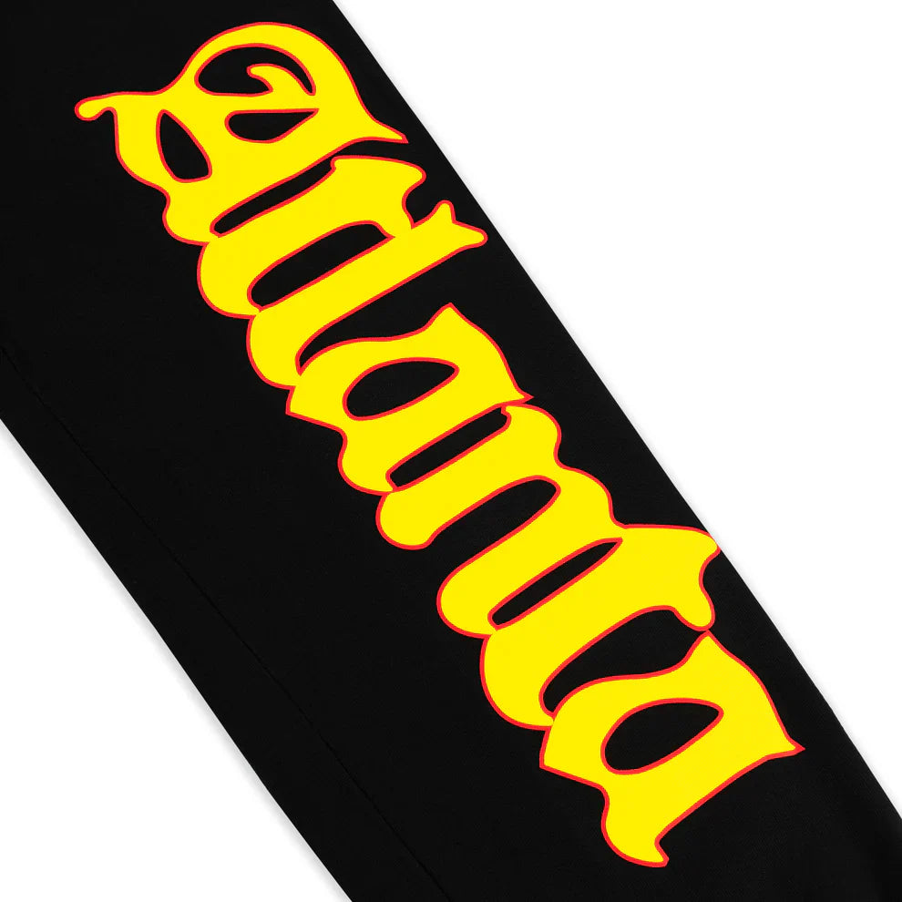 The word Atlanta appears in large, bold, yellow Gothic-style letters with a red outline on a black background, reflecting the flame logo and star print featured on Sp5der Sweatpants – Unisex Black Cotton Sweatpants.