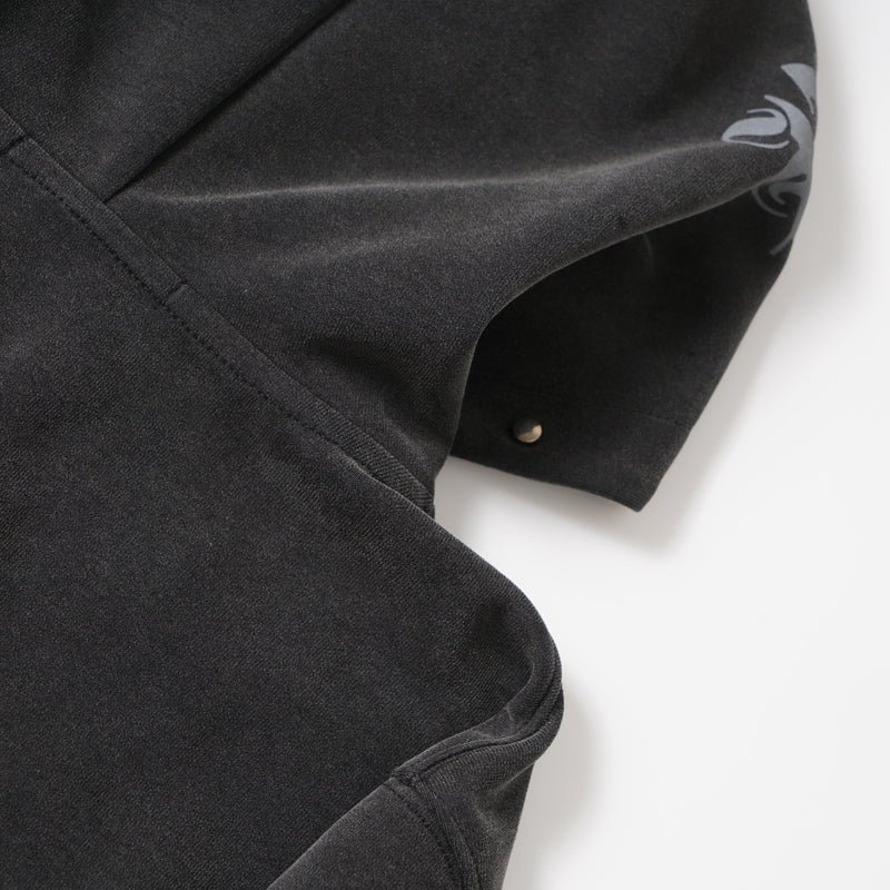 Close-up of black hoodie sleeve seam and washed fabric texture with partial graphic detail