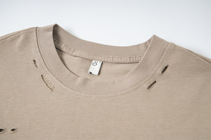 Close-up of beige crew neckline with distressed holes and stitched collar seam