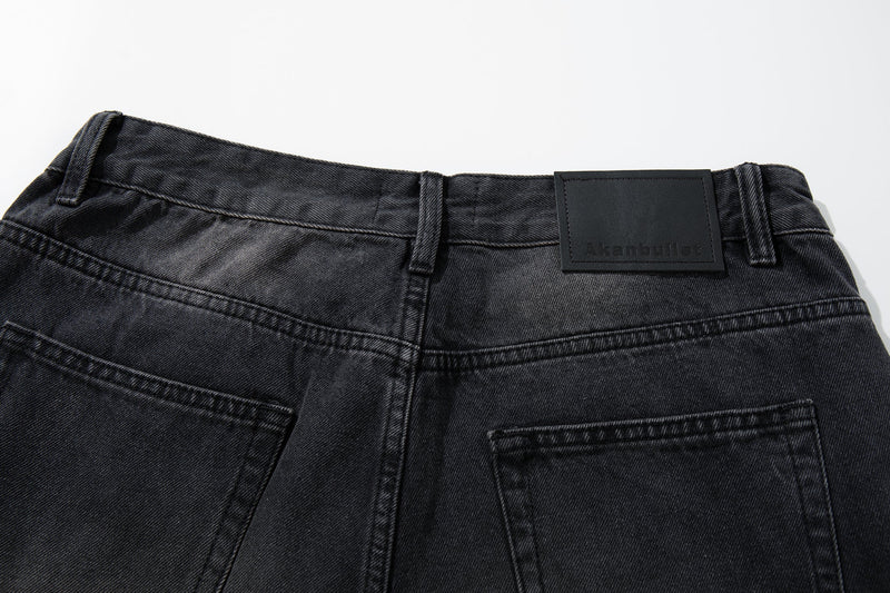 Close-up of back waistband on dark faded jeans with black leather logo patch and belt loops