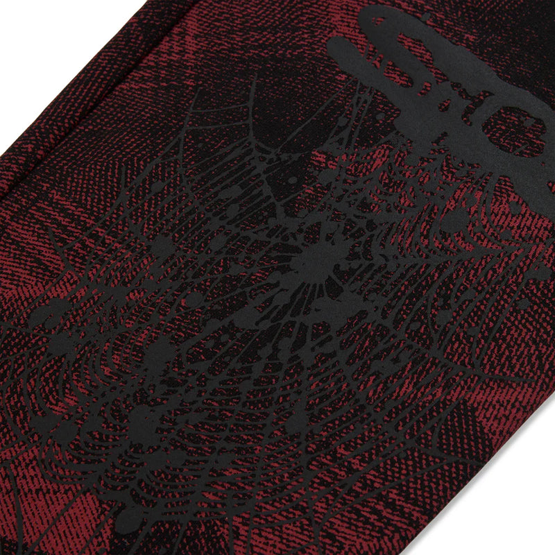 A close-up of Sp5der Sweatpants – Unisex Red and Black Patterned Cotton Sweatpants with graphic detail, featuring a black spider web design and bold black text.