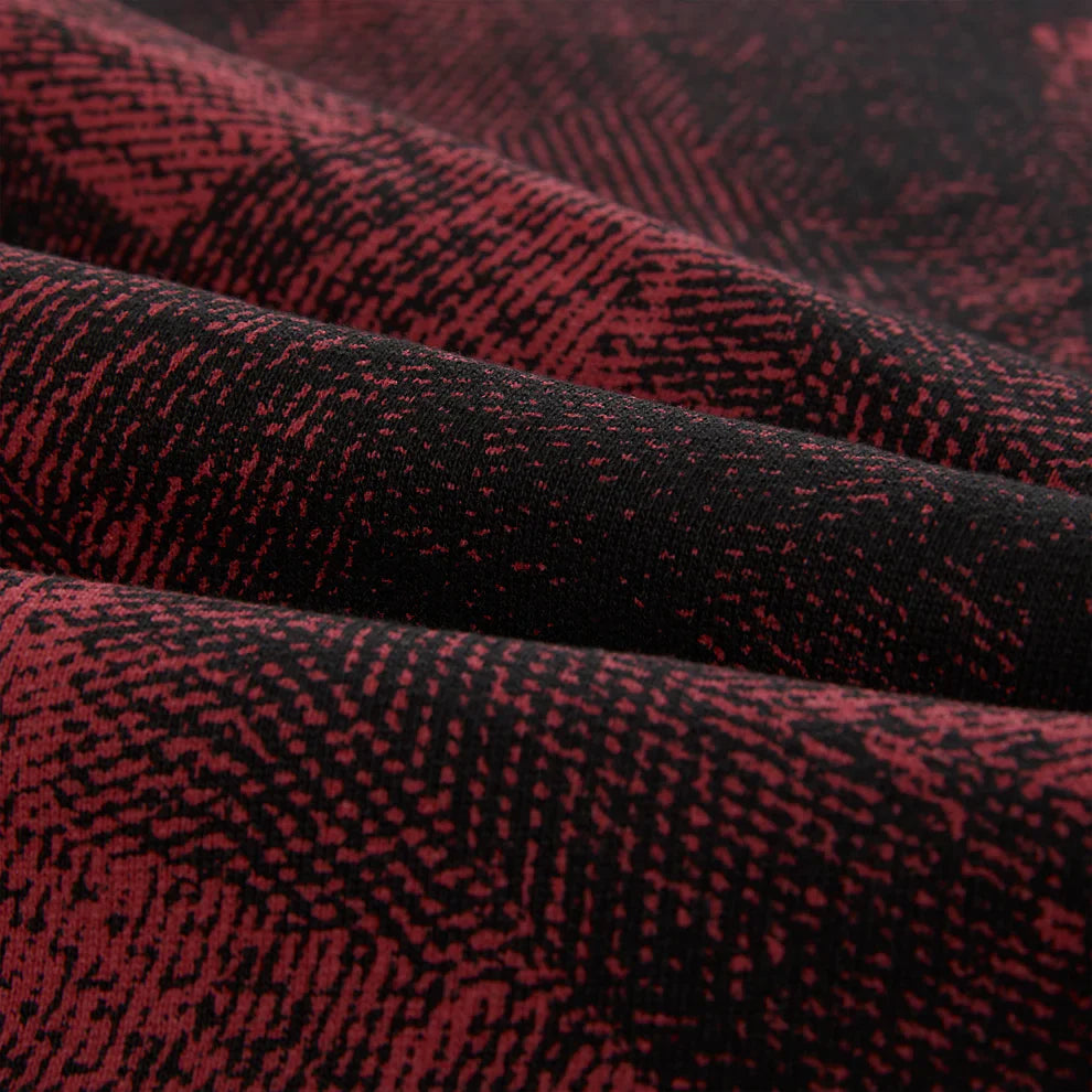 Close-up of Sp5der Sweatpants—unisex red and black patterned cotton sweatpants with graphic detail. Features wavy lines, small dots, and a soft, textured fabric ideal for streetwear or casual wear.