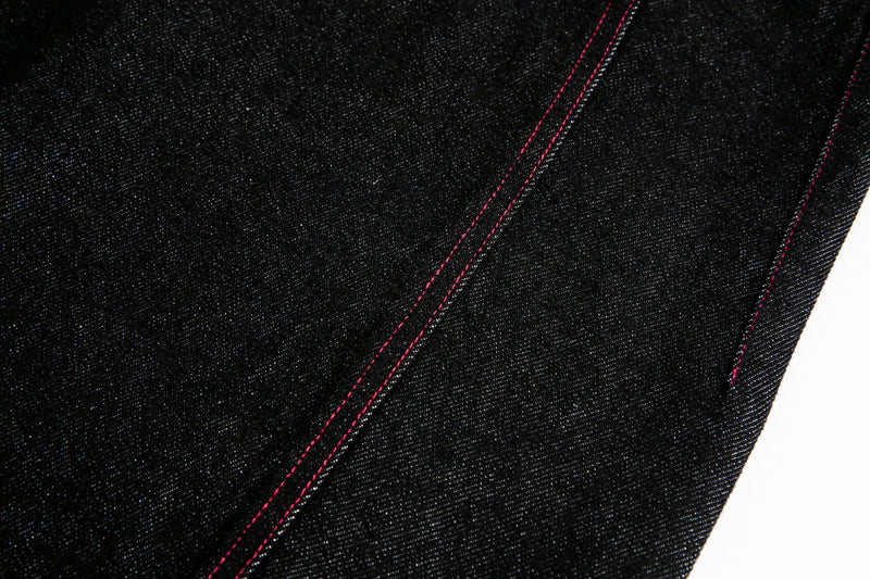 Close-up of black denim leg panel with red topstitching