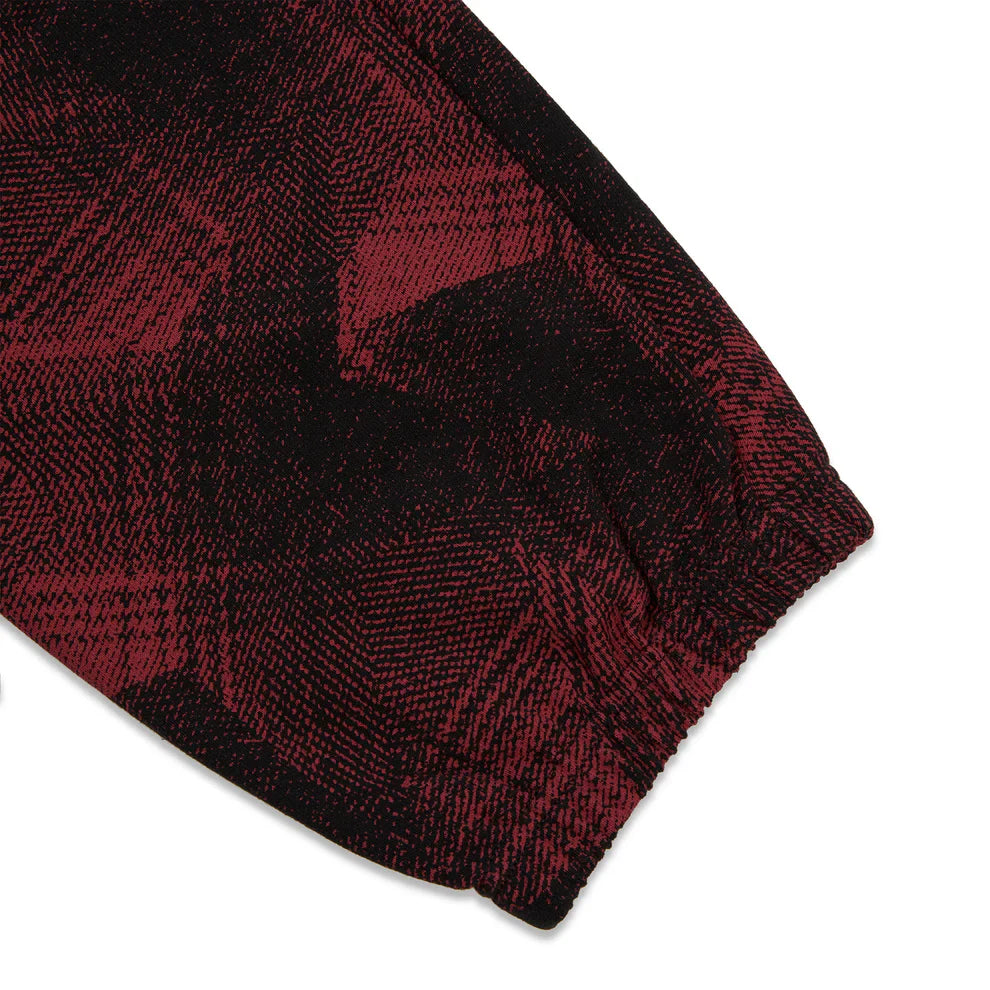 Close-up of a sleeve cuff in red and black plaid, with an elastic wrist—mirroring the bold style of Sp5der Sweatpants: unisex, cotton, graphic-detailed pants featuring a striking red and black pattern.