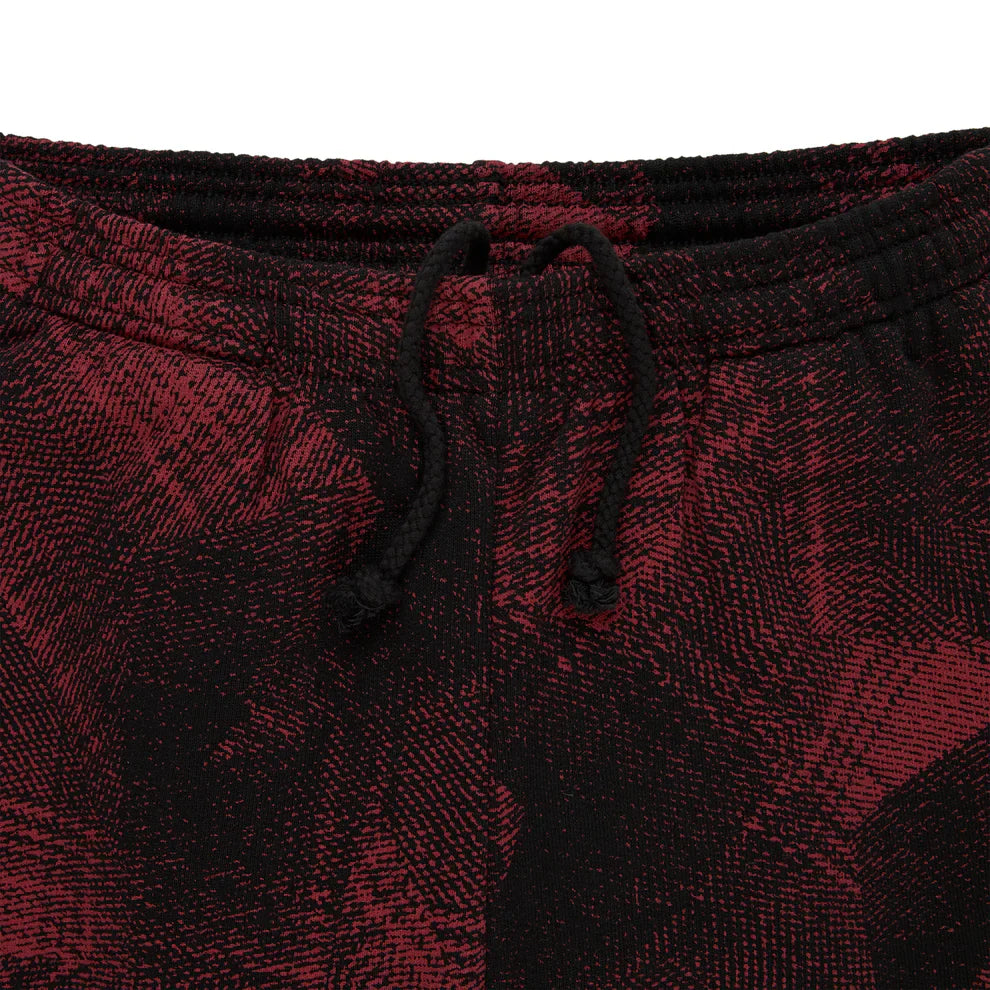 Close-up of the Sp5der Sweatpants—unisex red and black patterned cotton joggers with graphic detail and a front black drawstring, ideal for giving your streetwear look an edgy upgrade.