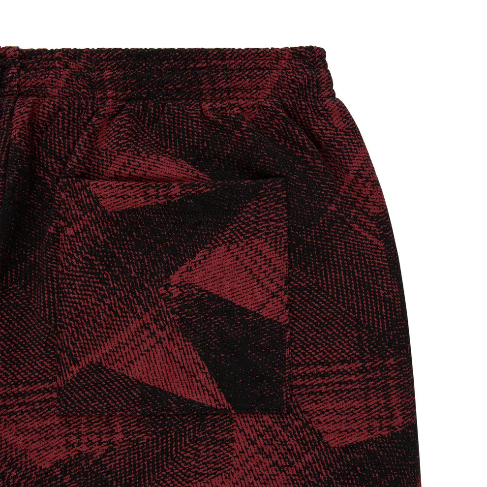 Close-up of Sp5der Sweatpants—unisex cotton joggers in red and black with a bold graphic pattern, elastic waistband, and front pocket, ideal for streetwear fans.