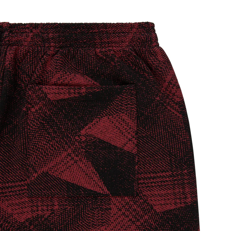 Close-up of Sp5der Sweatpants—unisex cotton joggers in red and black with a bold graphic pattern, elastic waistband, and front pocket, ideal for streetwear fans.