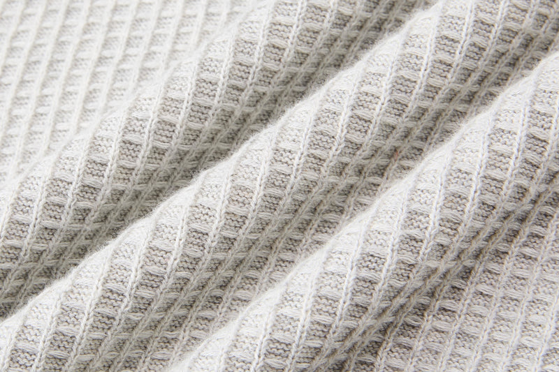 Close-up of cream waffle knit sweater fabric with a soft ribbed texture and relaxed cotton blend feel