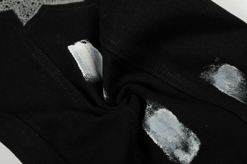 Close-up of black denim with white paint-like brush marks on the leg