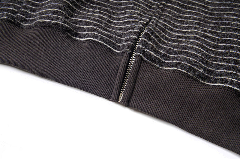 Close-up of ribbed hem and bottom zipper on black striped knit hoodie