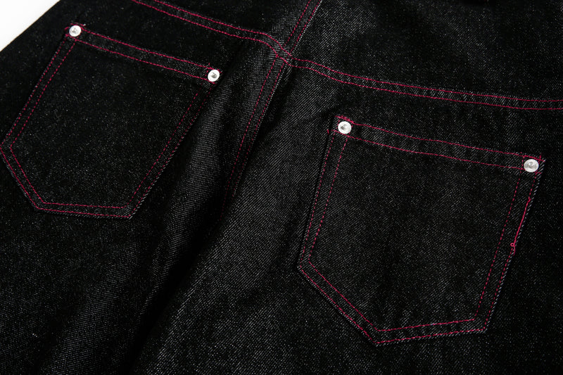 Back pocket detail on black denim pants with red stitching and silver rivets
