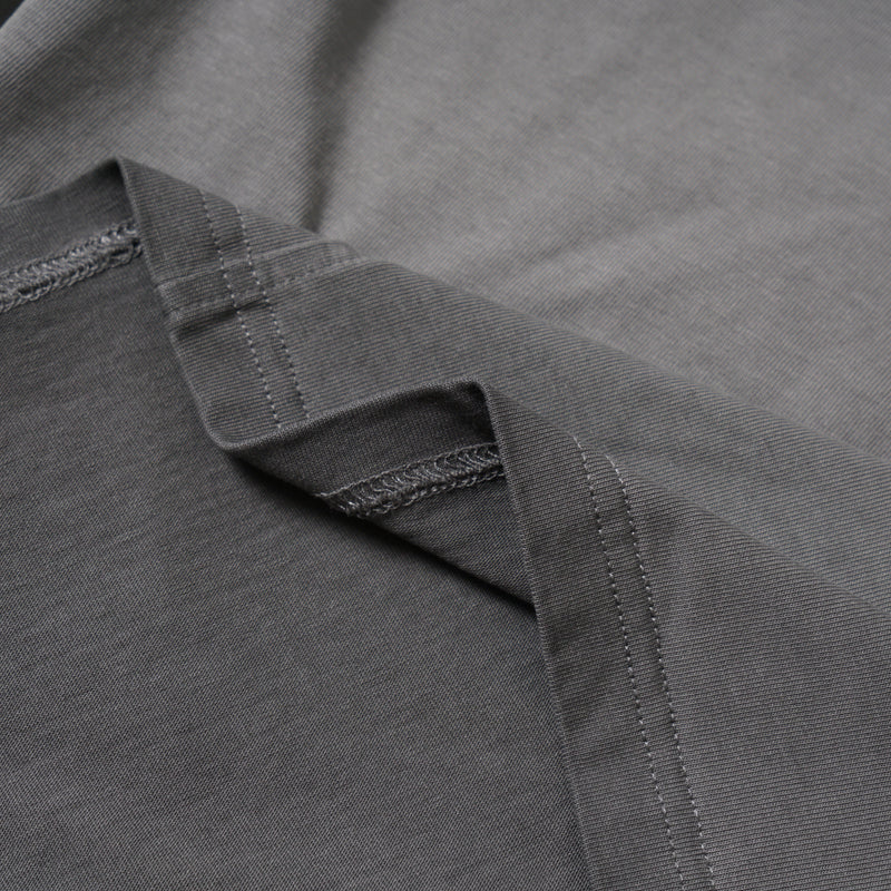 Close-up of layered sleeve construction and stitching on washed grey tee fabric