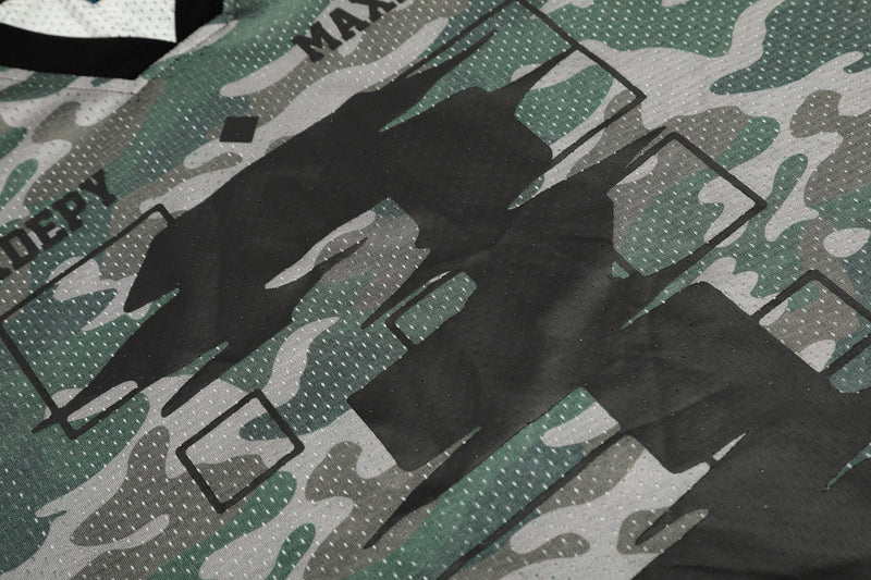 Close-up of green and gray camo mesh jersey fabric with bold black graphic lettering and perforated texture