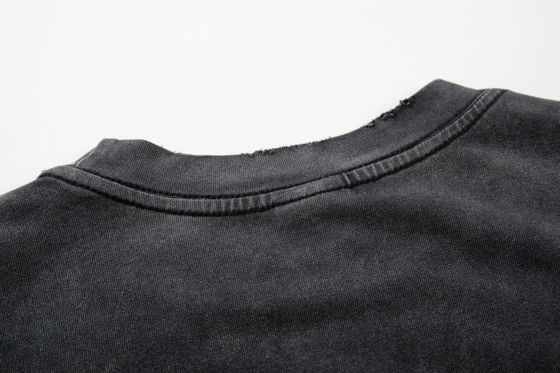 Close-up of a washed black vintage T-shirt collar with distressed stitching and grunge-style fade texture
