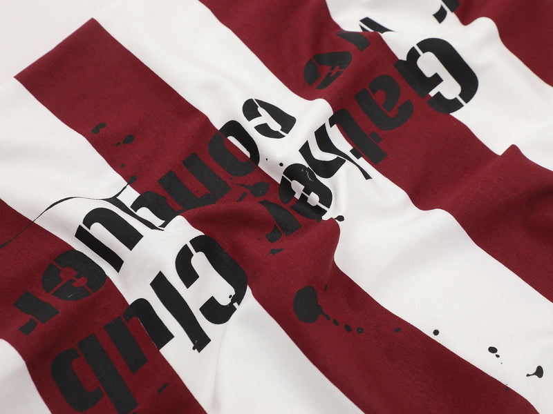 Close-up of a burgundy and white striped graphic tee with bold black lettering and a distressed streetwear print