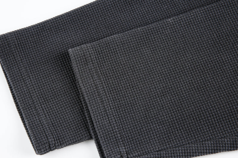 Close-up of black waffle knit sleeve end and cuff detail