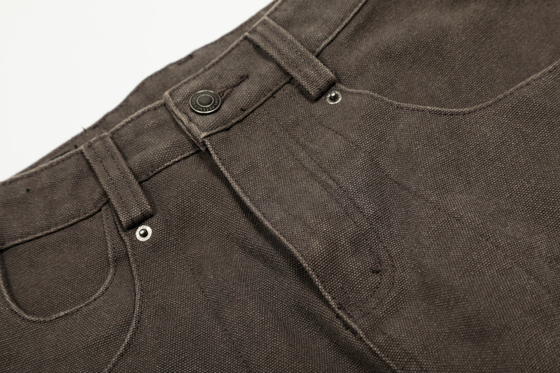 Close-up of brown pants waist showing button, belt loops, and curved pocket opening