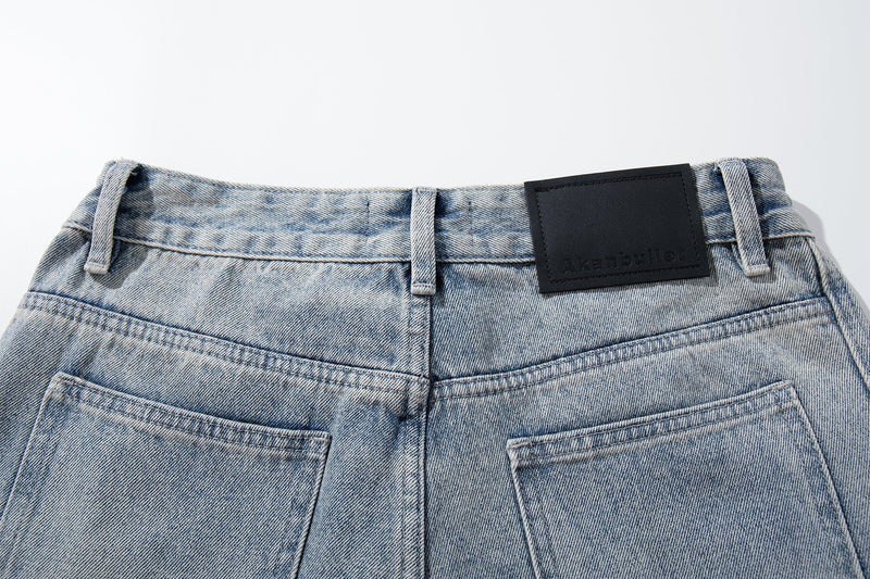 Close-up of the back waistband on light wash jeans with black leather-style patch and belt loops