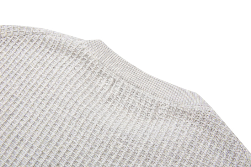 Close-up of a cream waffle knit short-sleeve sweater with relaxed fit and textured ribbed stitching