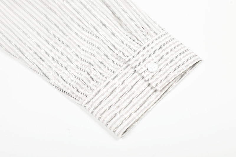 Close-up of buttoned cuff on cream striped long-sleeve shirt