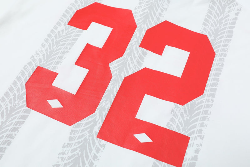 White soccer polo shirt with large red 32 graphic and faint gray tire track pattern on the back